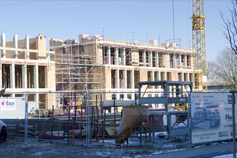 Mehrfamilienhaus im Winterrohbau mit Schnee und Baukran